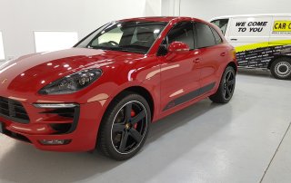 A freshly cleaned Red Porsche Macan S, that has had a full car detailing service on it, in a showroom